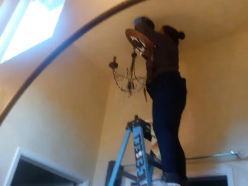 Electrician installing a chandelier in a Milo residence